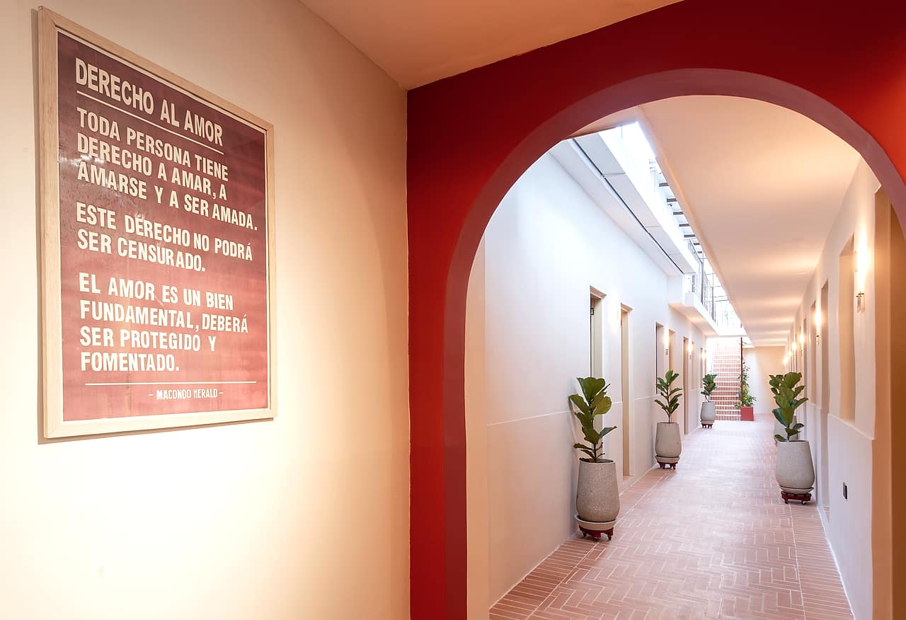 Arco rojo sobre el corredor de baldosas de terracota en La Casa del Huésped