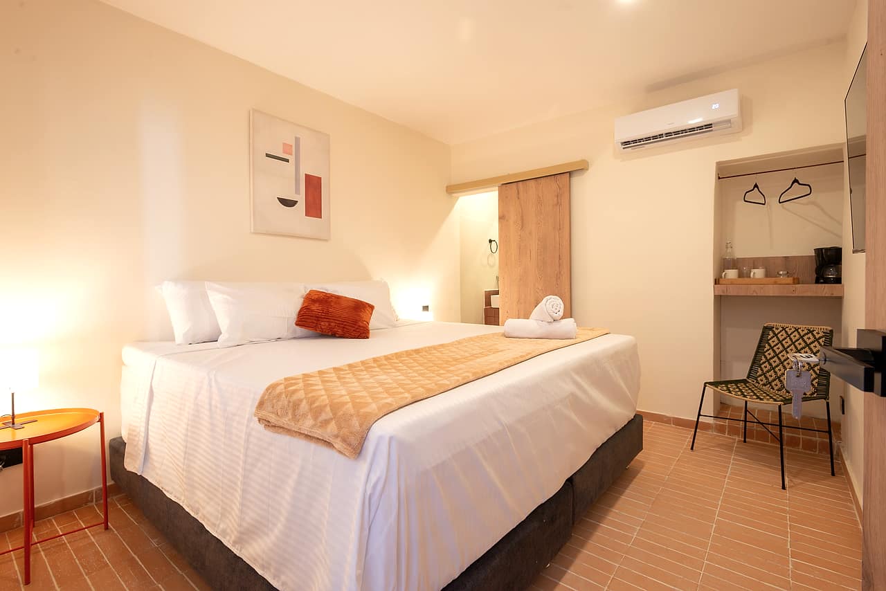 Habitación renovada con cama king y cojín naranja